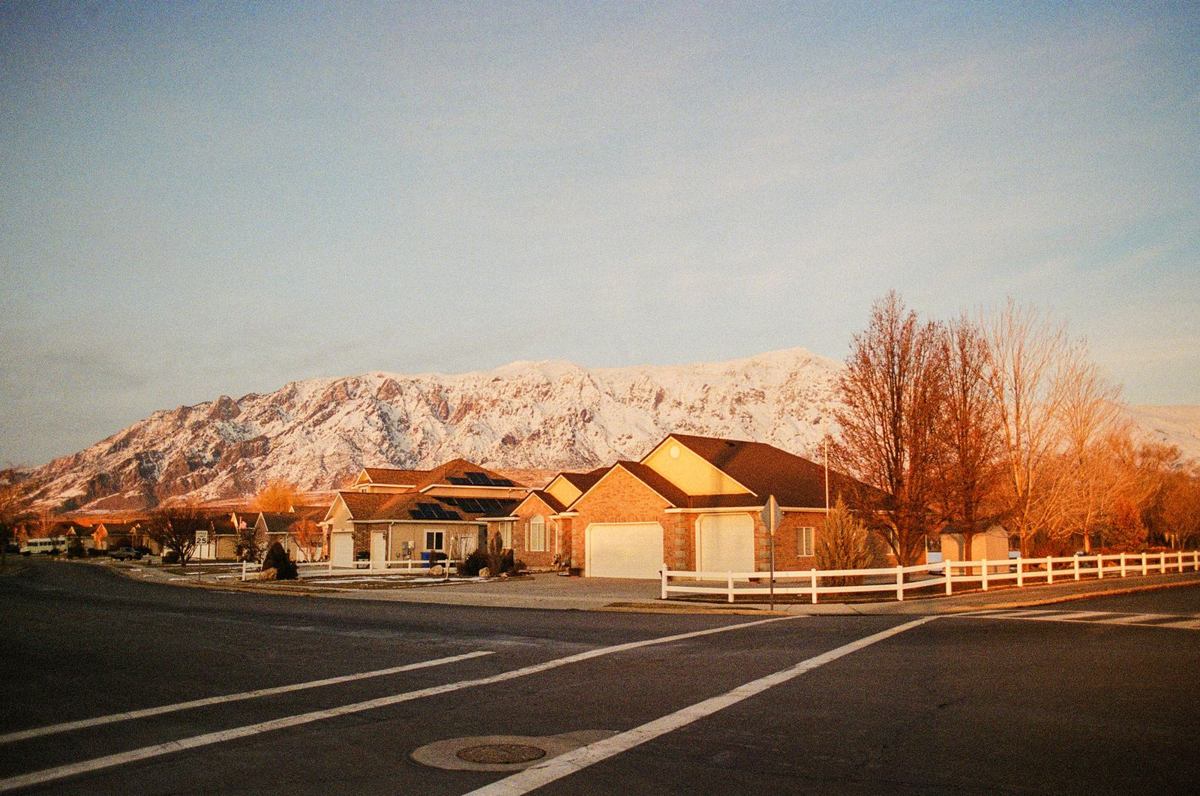 Row of suburban homes on a quiet street with the snow-capped Front Range rising behind them at first light